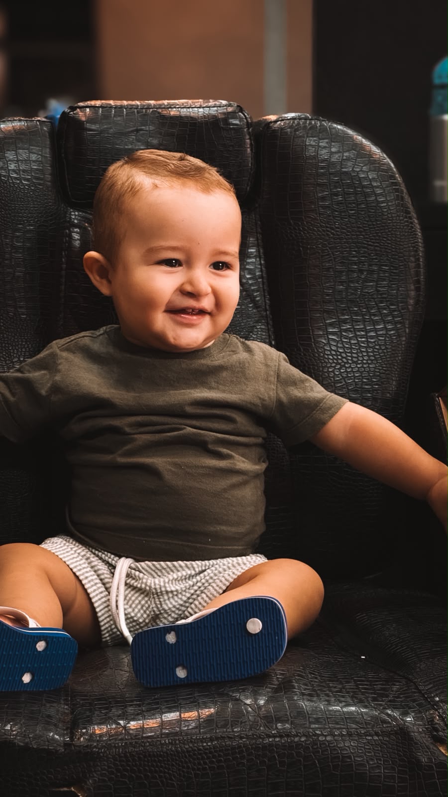 Criança sentada na cadeira da barbearia